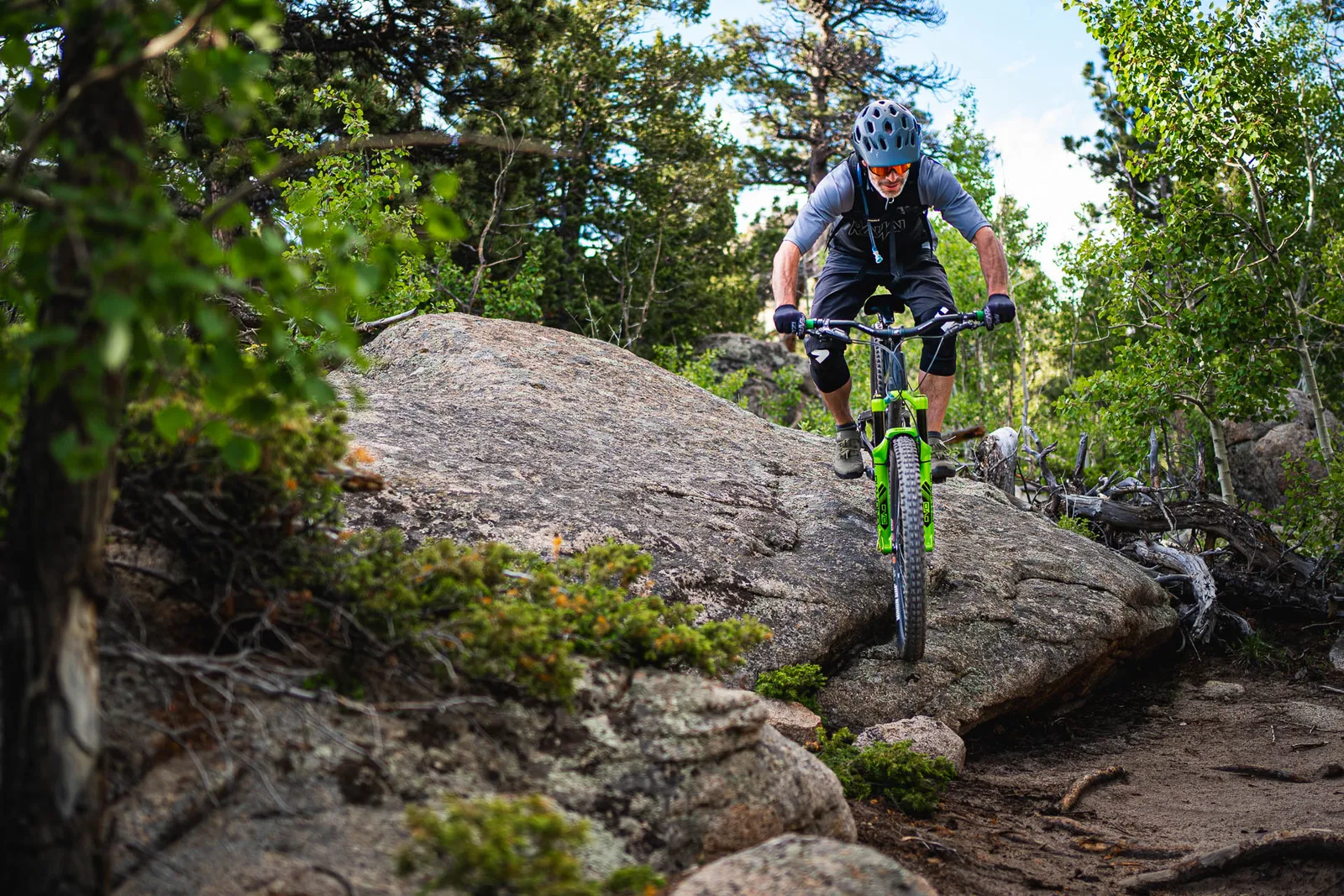 A mountain biker riding through large rocks and pine trees